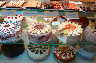 Eine Glasvitrine im Verkaufsraum, die mit einer vielseitigen Kuchen- und Tortenauswahl gefüllt ist