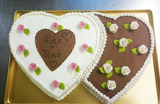 Ein Hochzeitskuchen, der die Form von zwei Herzen hat und mit Zuckerblumen verziert ist